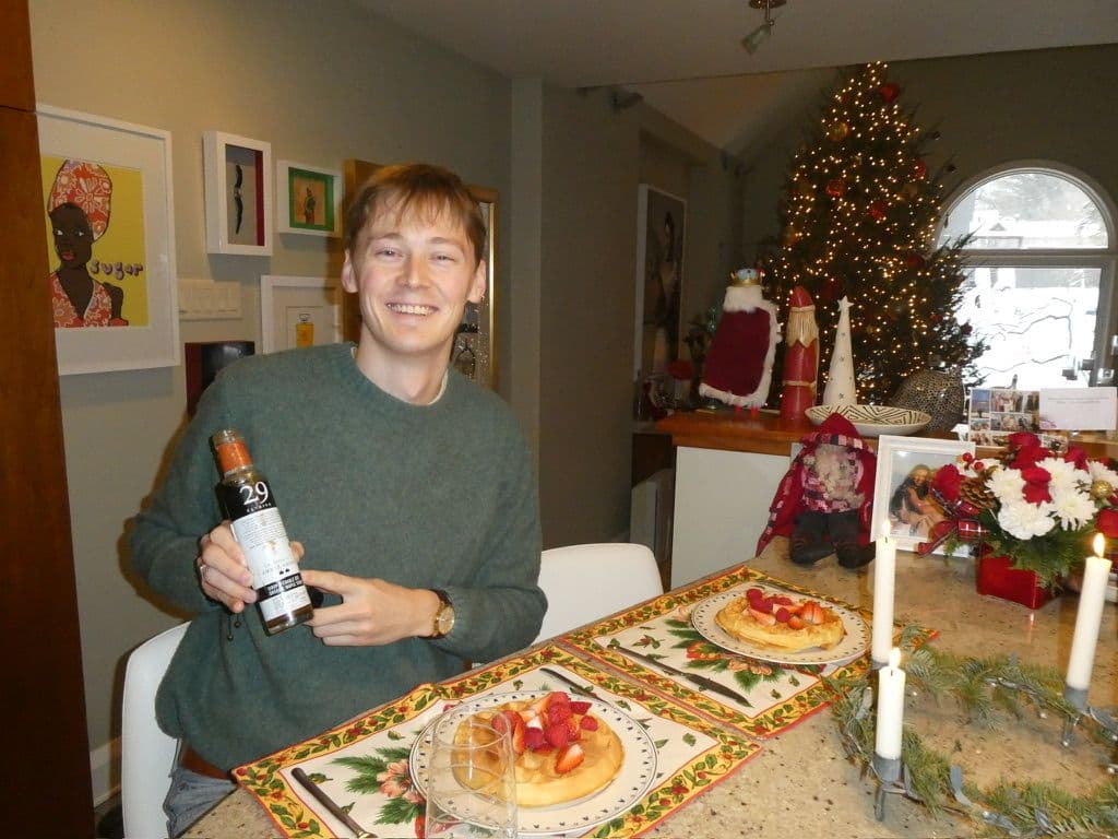 me holding a bottle of maple syrup in a home with pancakes and christmas tree